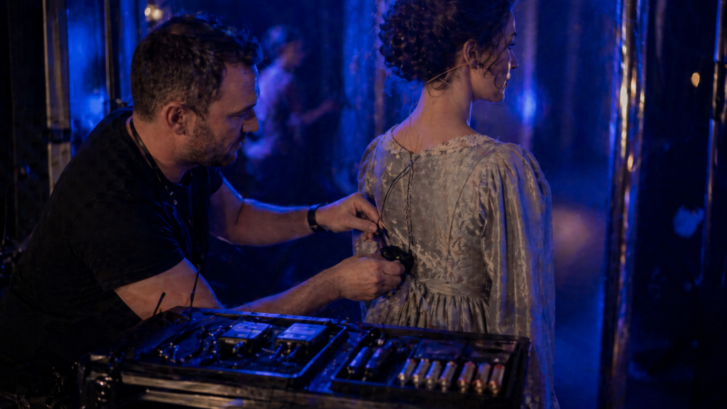 Sound No.2 swapping a radio mic pack on an actor during a backstage quick change